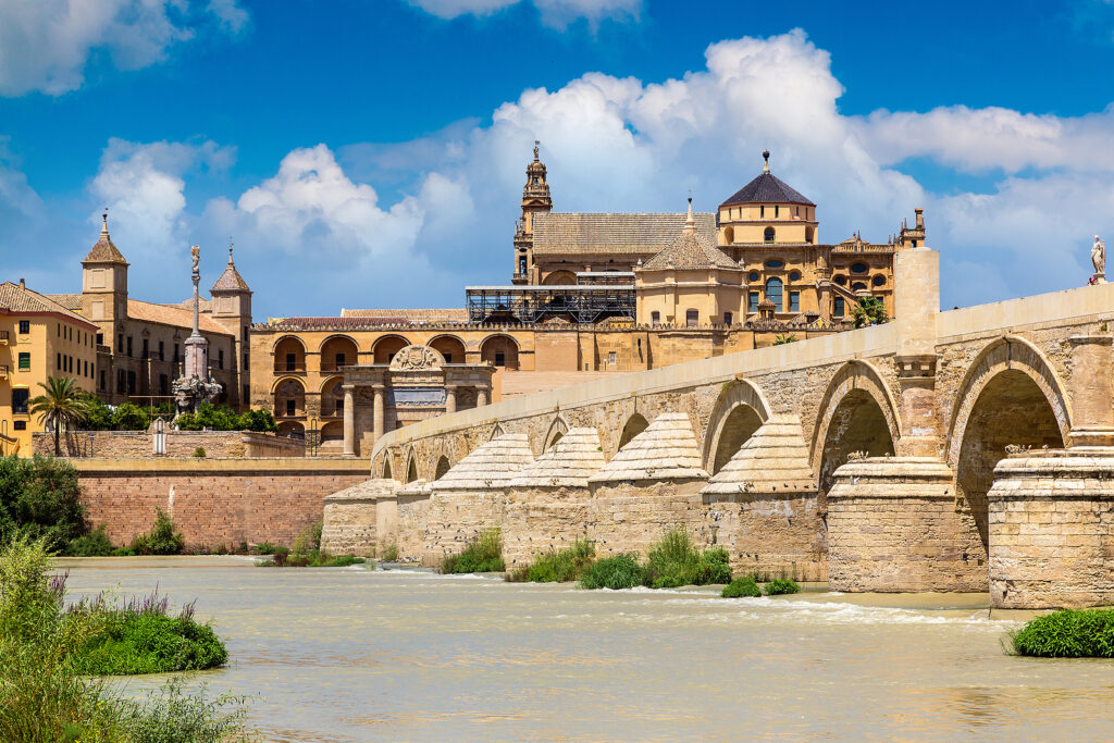 The Great Mosque (Mezquita Cathedral) and Roman Bridge on Guadalquivir river in Cordoba in a beautiful summer day, Spain